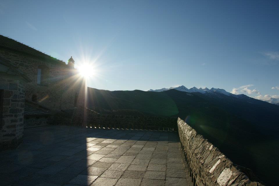 Terrazza in pietra della Sacra di San Michele in controluce con sole e montagne