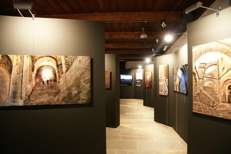 Corridoio espositivo con soffitto a travi e grandi stampe retroilluminate della Sacra