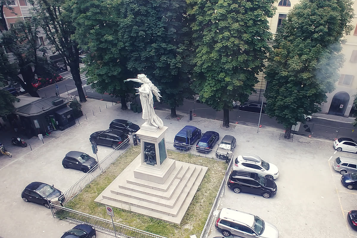Veduta dall'alto di una piazza di Milano con statua alata e auto parcheggiate
