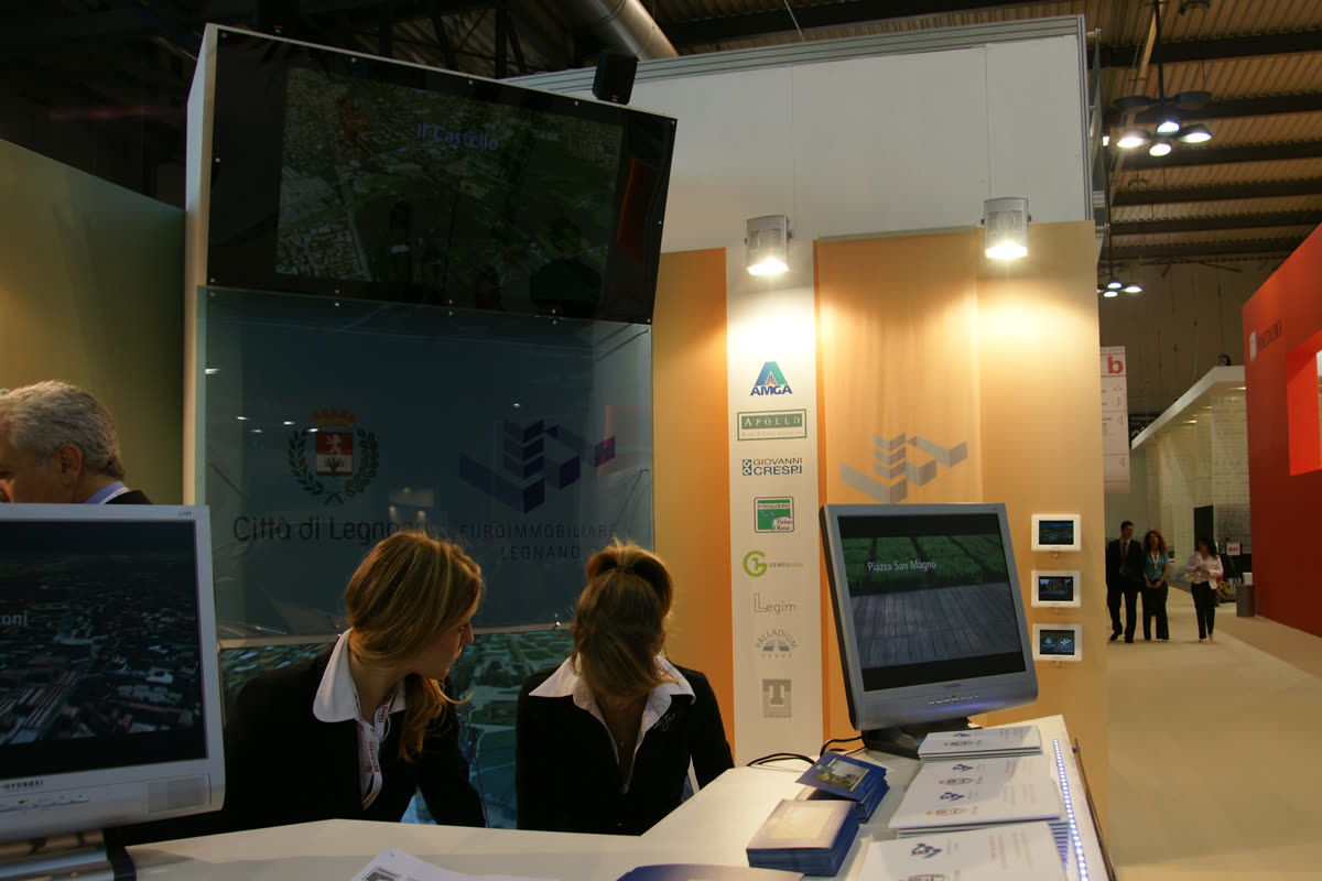 Hostess allo stand davanti al monolite-schermo con il render del Castello