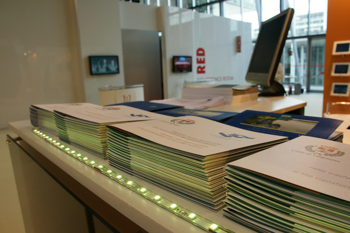 Pile di brochure istituzionali su banco luminoso a LED