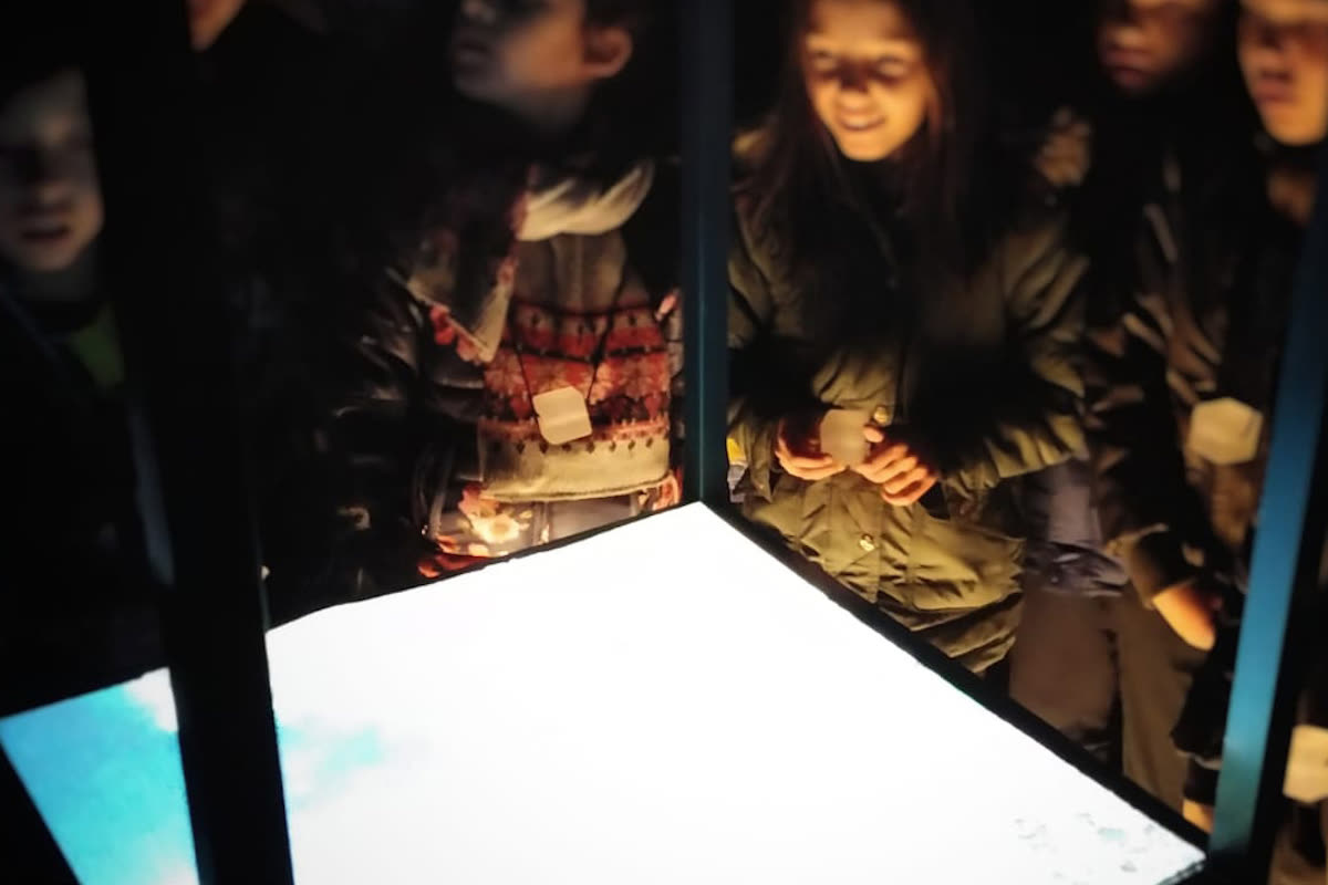Bambini raccolti al buio attorno a un tavolo luminoso della parte oscura