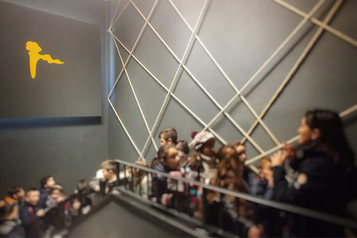 Gruppo di bambini su una scala con corde tese e silhouette gialla del Piccolo Principe
