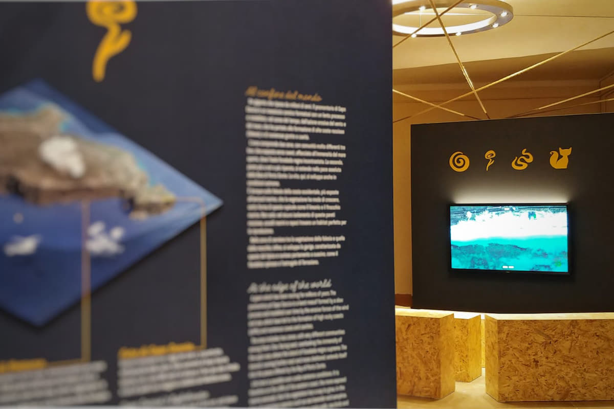 Pannello espositivo con mappa isometrica 3D e schermo a parete che mostra la costa dall'alto