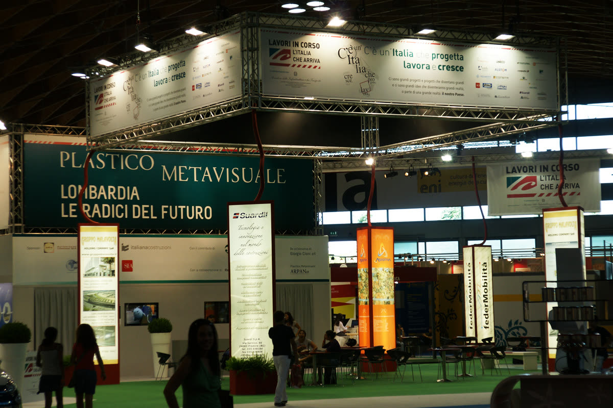 Stand espositivo del Padiglione Lombardia con insegne e visitatori al Meeting di Rimini