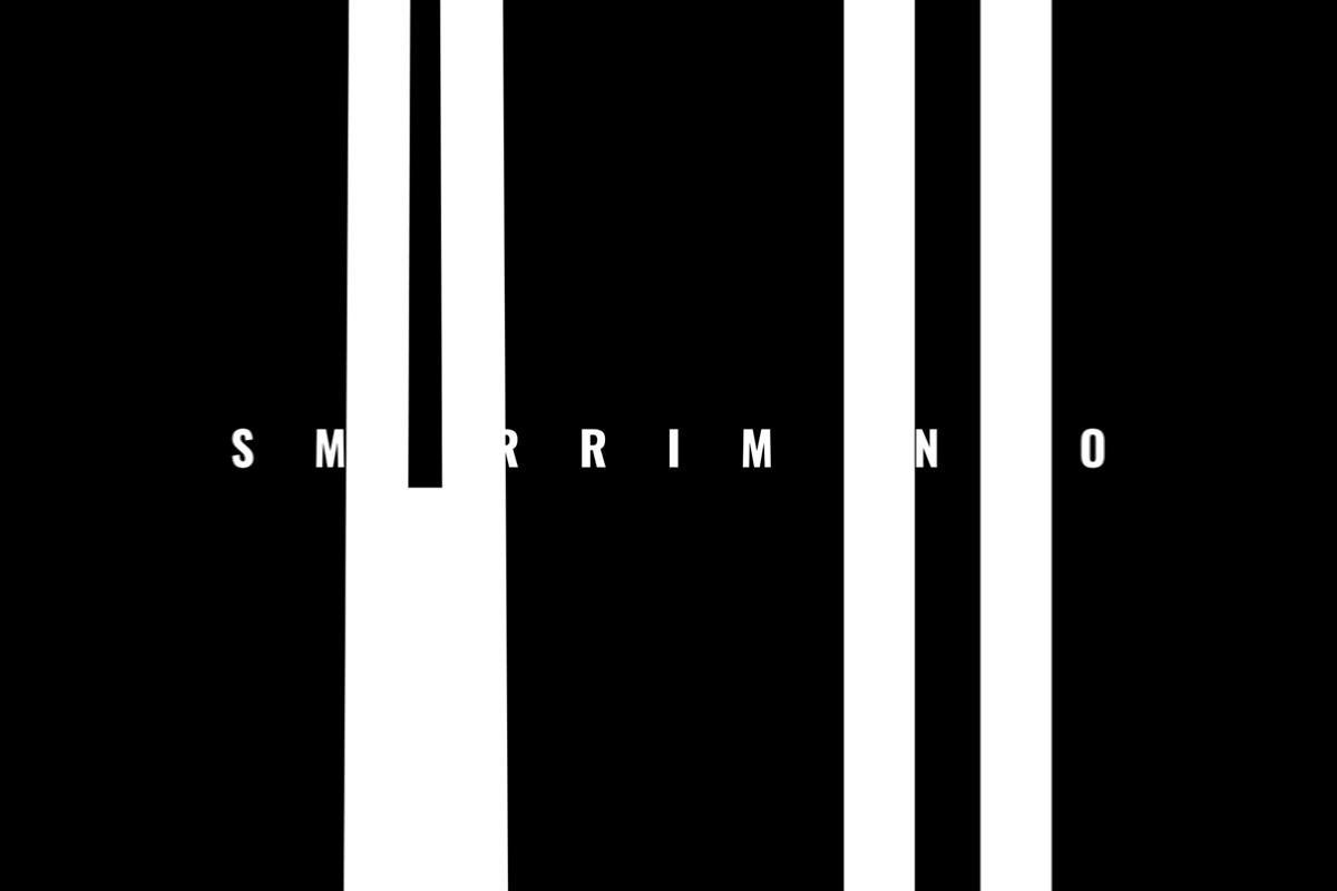 Context: fotogramma in bianco e nero con la parola SMARRIMENTO interrotta da barre verticali