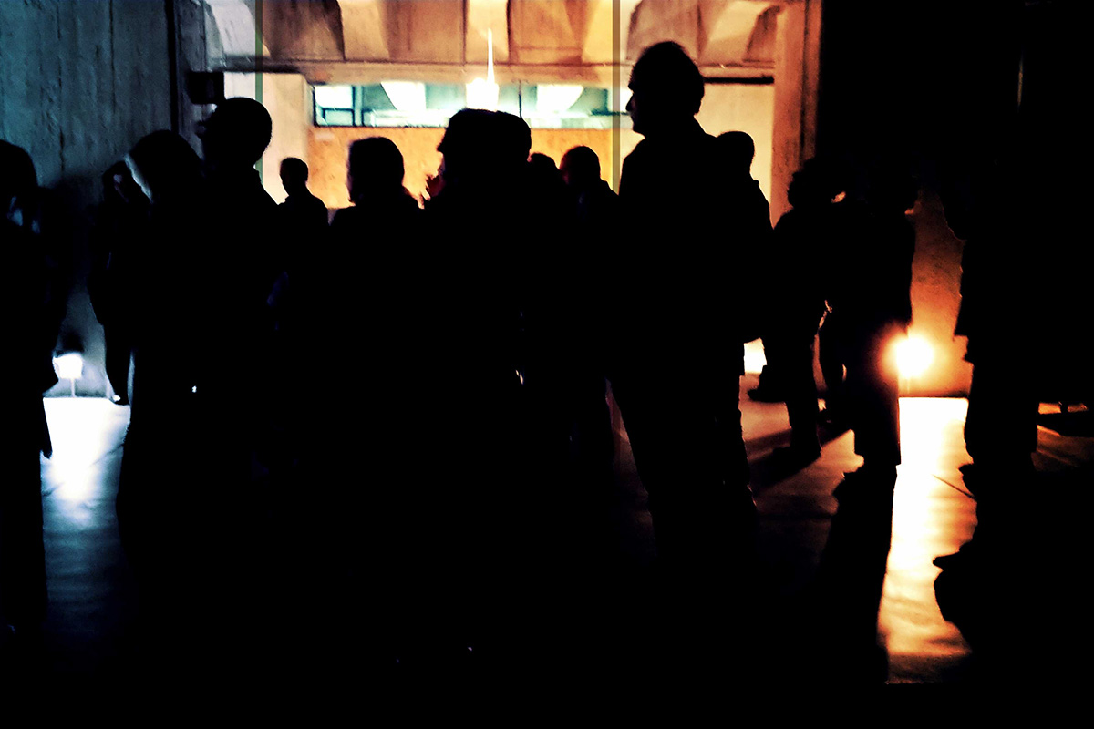Sagome del pubblico controluce nello spazio in cemento del Memoriale della Shoah