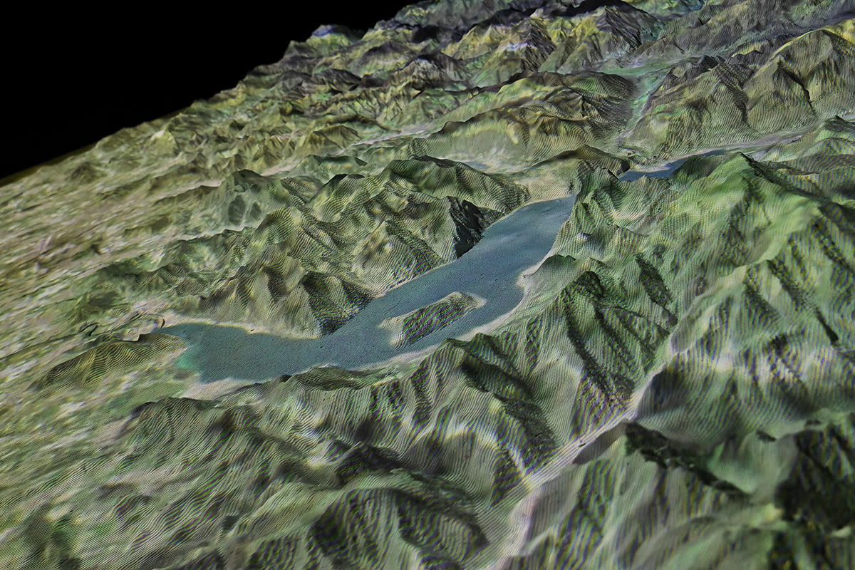 Dettaglio del Plastico metavisuale con rilievi montani verdi e un bacino lacustre