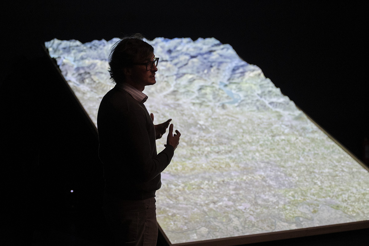 Paco Simone, in controluce, illustra il Plastico metavisuale con la mappa del territorio proiettata